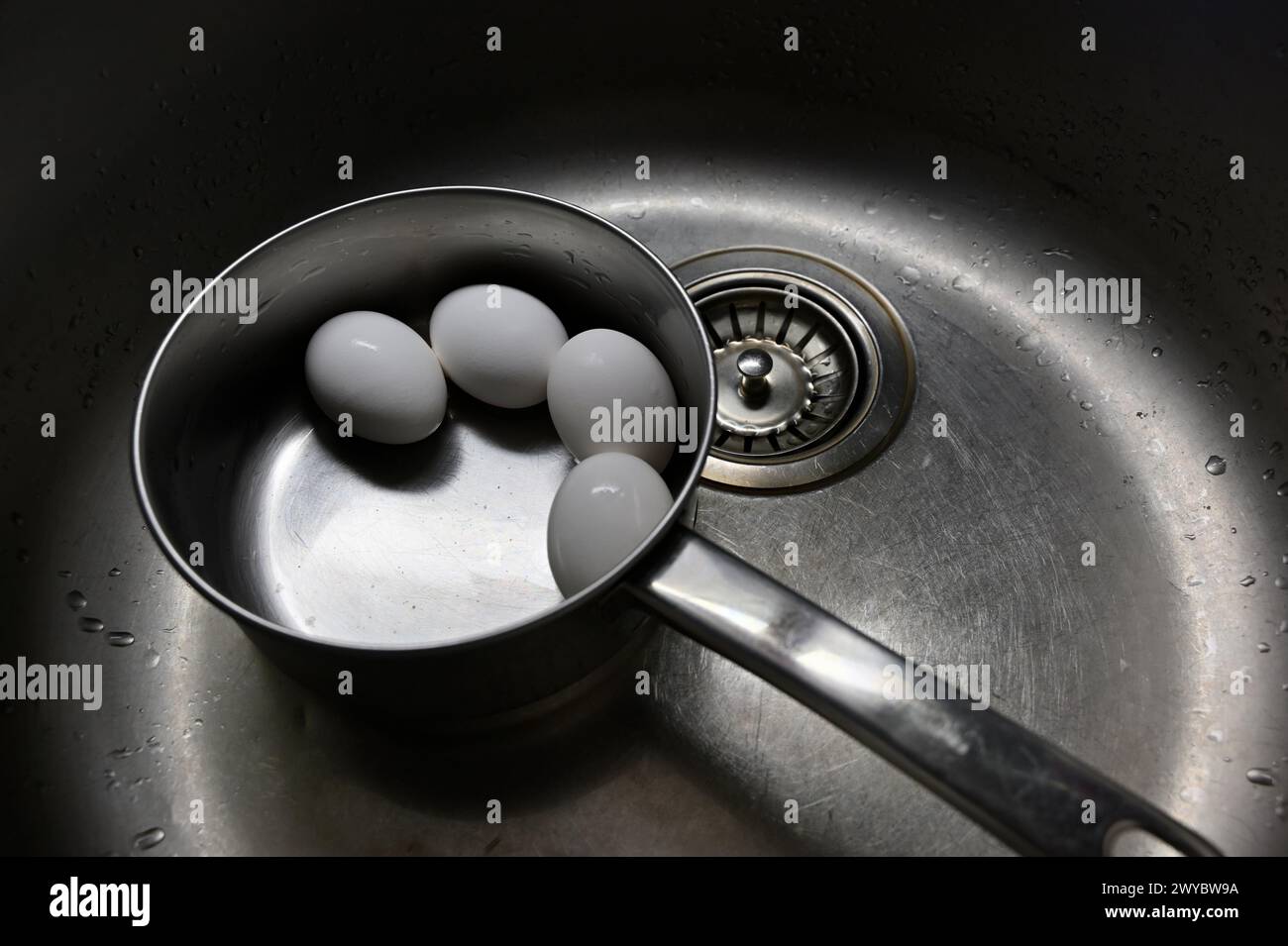 uova di pollo bollite in una pentola di metallo nel lavandino della cucina Foto Stock