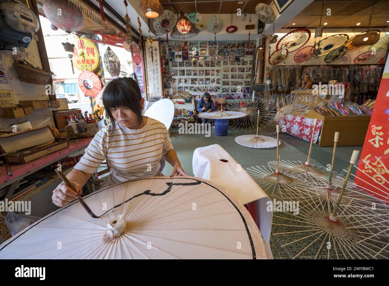 In un laboratorio, un artista decora un ombrello di carta con intricati disegni floreali Foto Stock