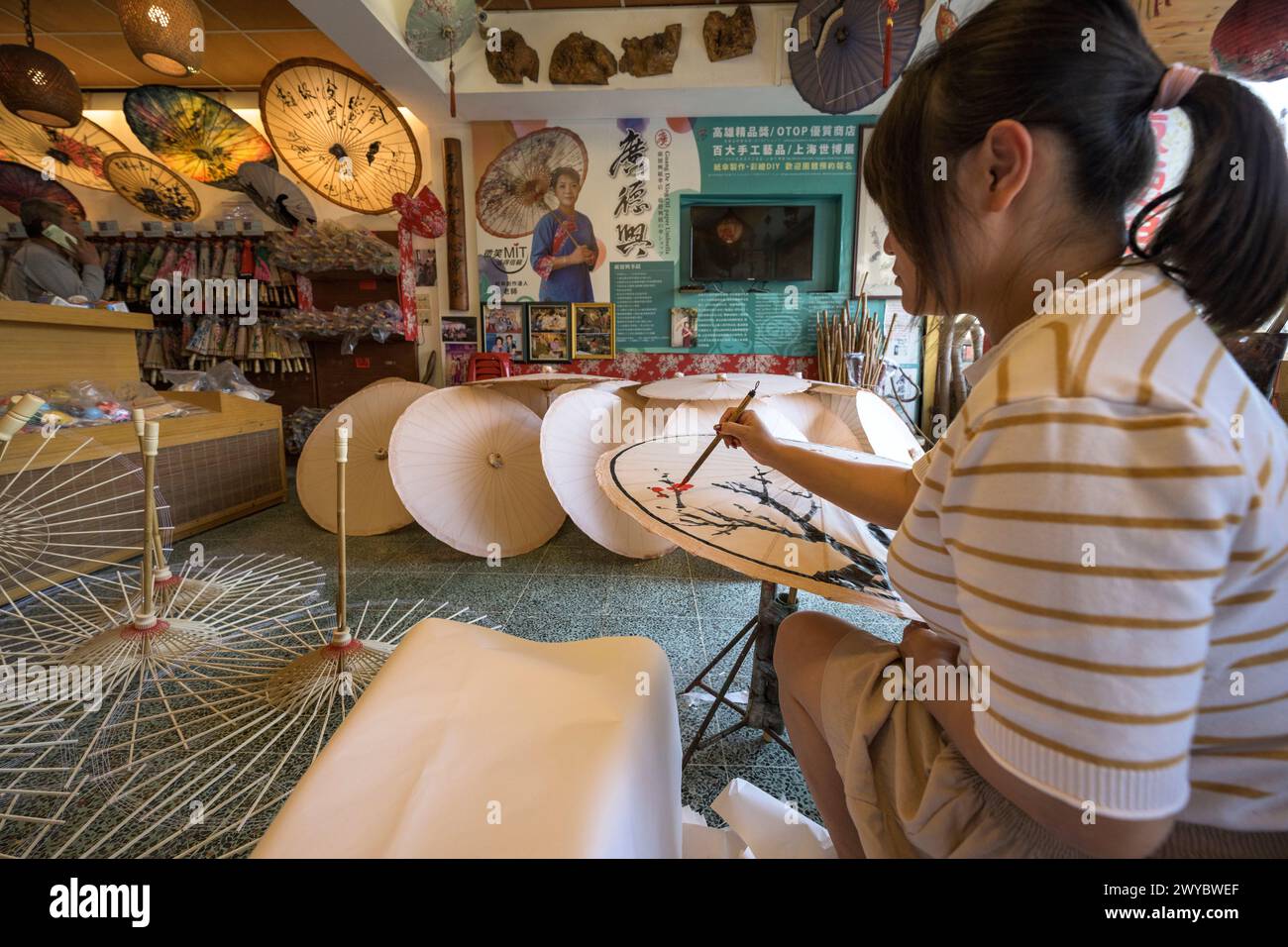 In un laboratorio, un artista decora un ombrello di carta con intricati disegni floreali Foto Stock