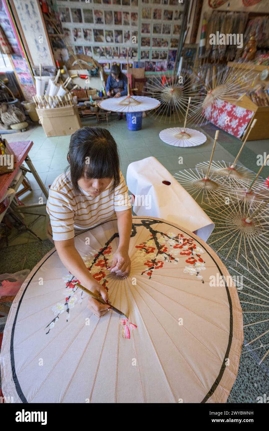 In un laboratorio, un artista decora un ombrello di carta con intricati disegni floreali Foto Stock