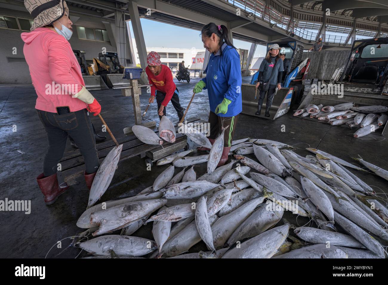 I pescatori di un mercato ittico che trattano pesce congelato si preparano a venderlo Foto Stock