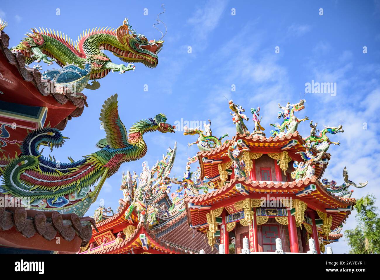 Colorate e intricate sculture di drago adornano il tetto di un tempio tradizionale taiwanese contro un cielo limpido Foto Stock