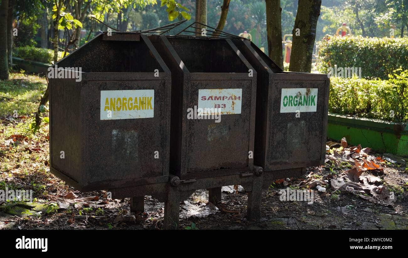 Un bidone arrugginito in un parco suddiviso in tre categorie di rifiuti: Rifiuti inorganici, rifiuti B3 e rifiuti organici Foto Stock