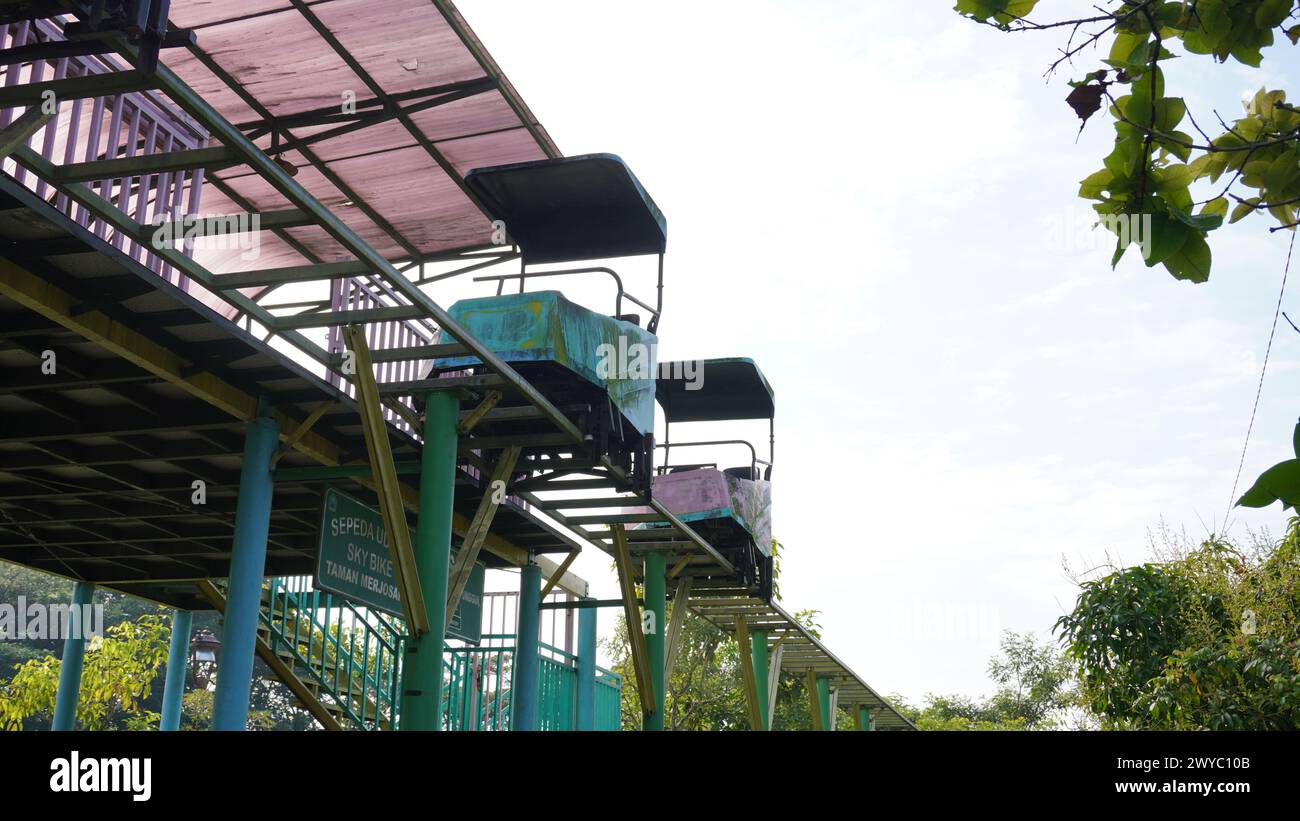 Giri in Sky bike a Taman Singha Malang, che non sono operativi da molto tempo e sono in stallo. Anche il treno e le rotaie sembrano arrugginiti Foto Stock