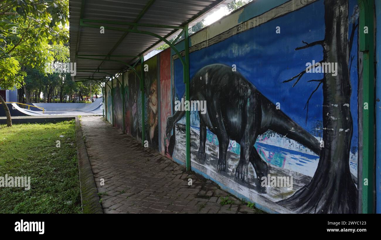 Il marciapiede al Singha Park Malang al mattino con vari tipi di murales sulle pareti Foto Stock