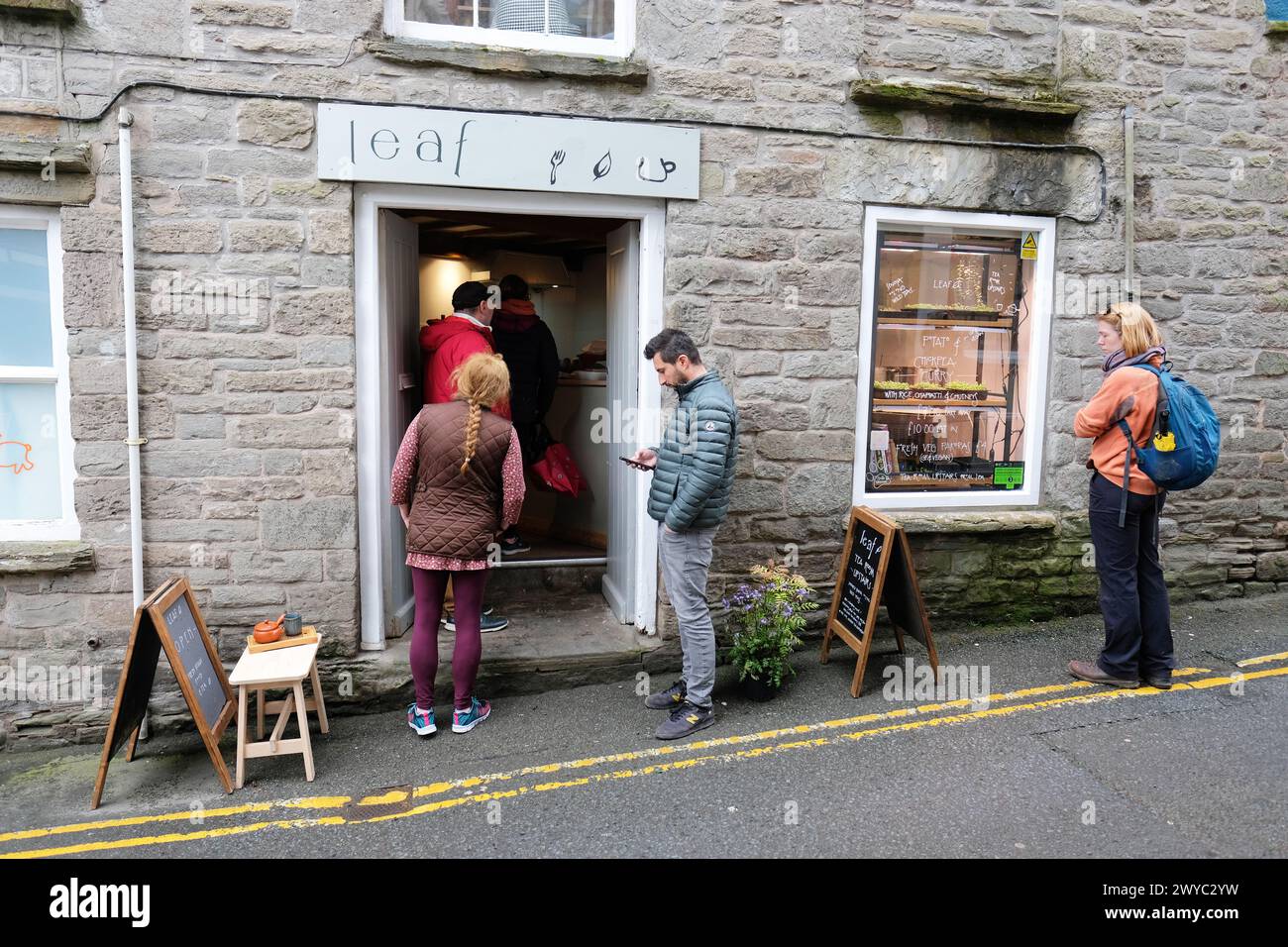 Hay on Wye Powys Wales - i clienti fanno la fila fuori da Leaf, un popolare caffè al curry e Tea Cafe nell'aprile 2024 Foto Stock