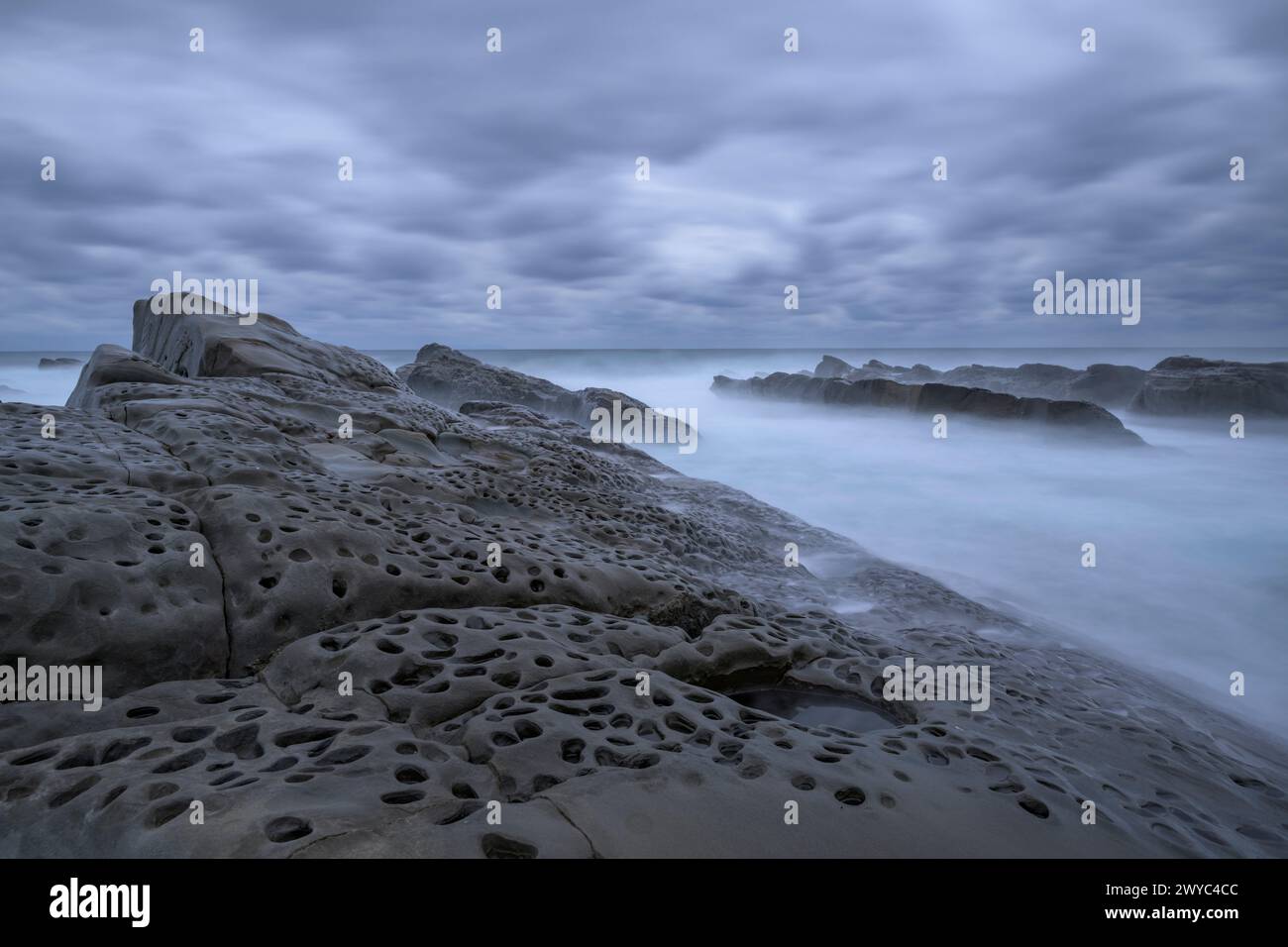 Atmosfera mistica con rocce lisce e intemperie su una costa frastagliata, sotto un cielo coperto Foto Stock