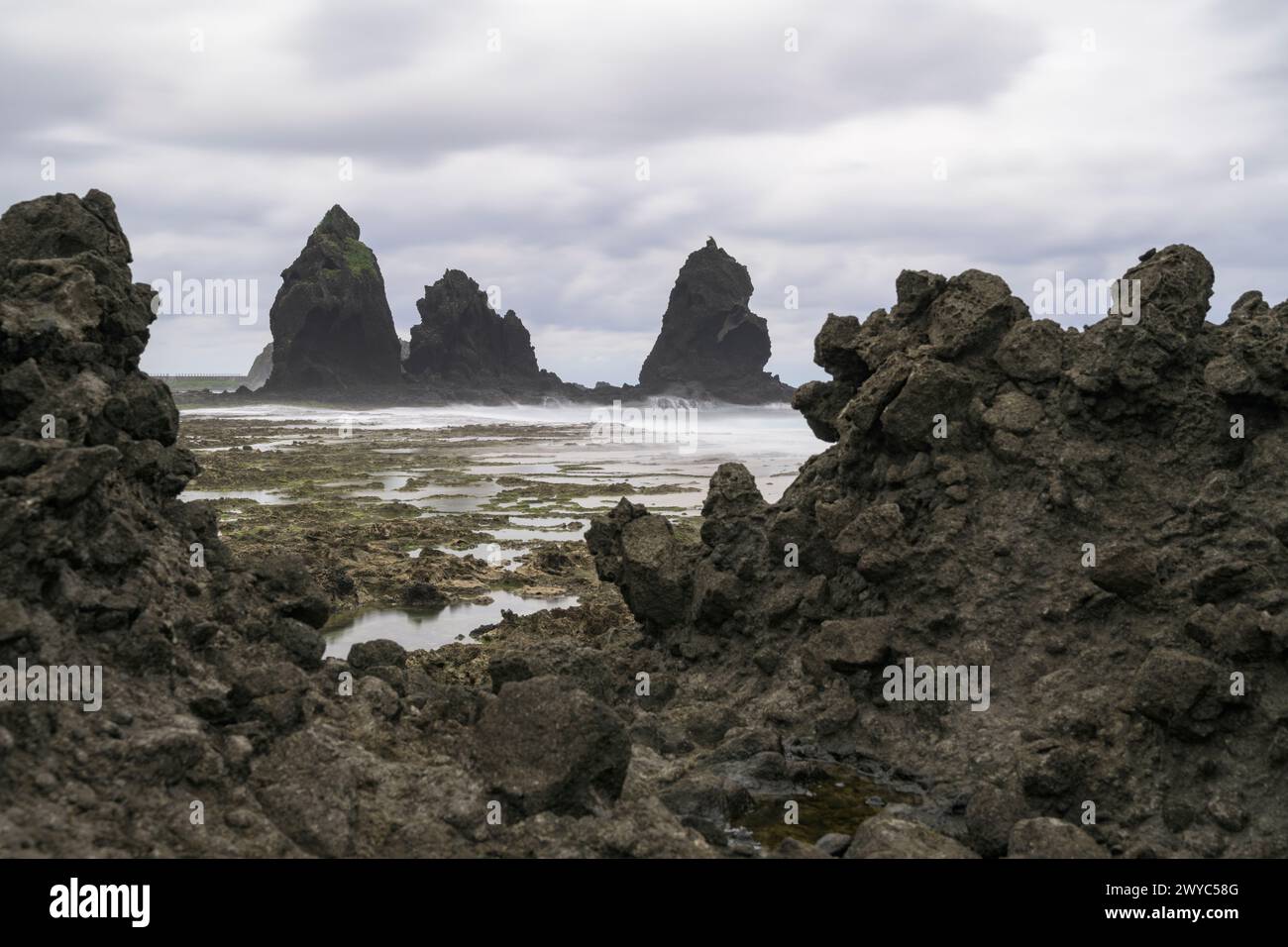 Nuvole minacciose si innalzano su una costa rocciosa con impressionanti formazioni rocciose che sporgono dal mare Foto Stock