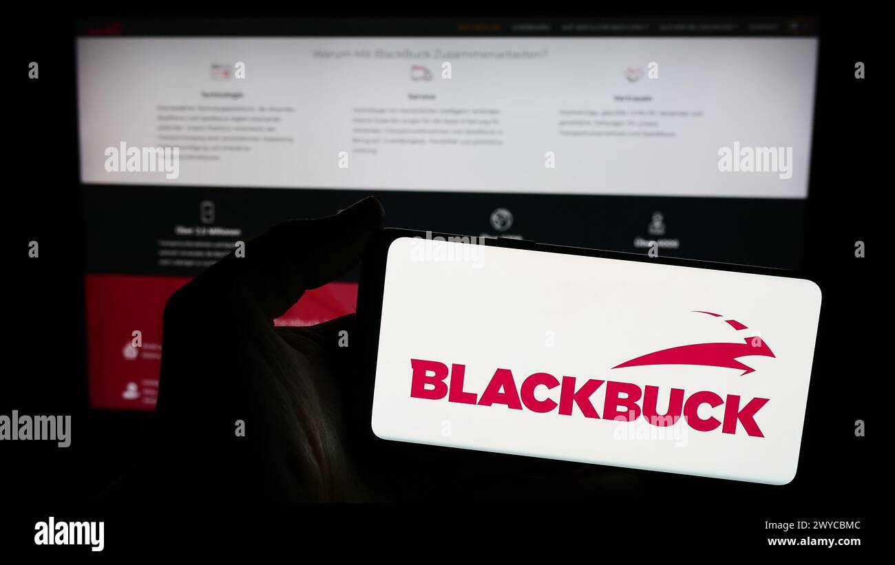 Persona che detiene lo smartphone con il logo dell'azienda Zinka Logistics Solutions Pvt. Ltd (BlackBuck) di fronte al sito web. Mettere a fuoco il display del telefono. Foto Stock