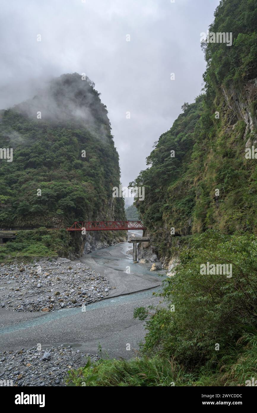 Una vista eterea e tranquilla di una gola di montagna nebbiosa con un fiume dolce che si snoda attraverso Foto Stock