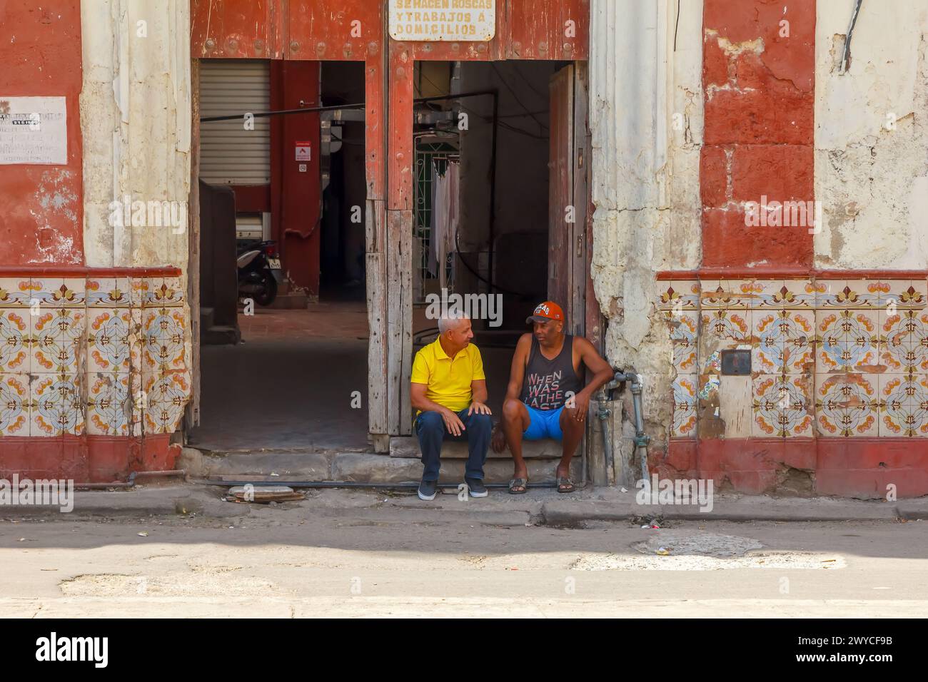 Due uomini cubani seduti a due passi da un vecchio edificio a l'Avana, Cuba Foto Stock