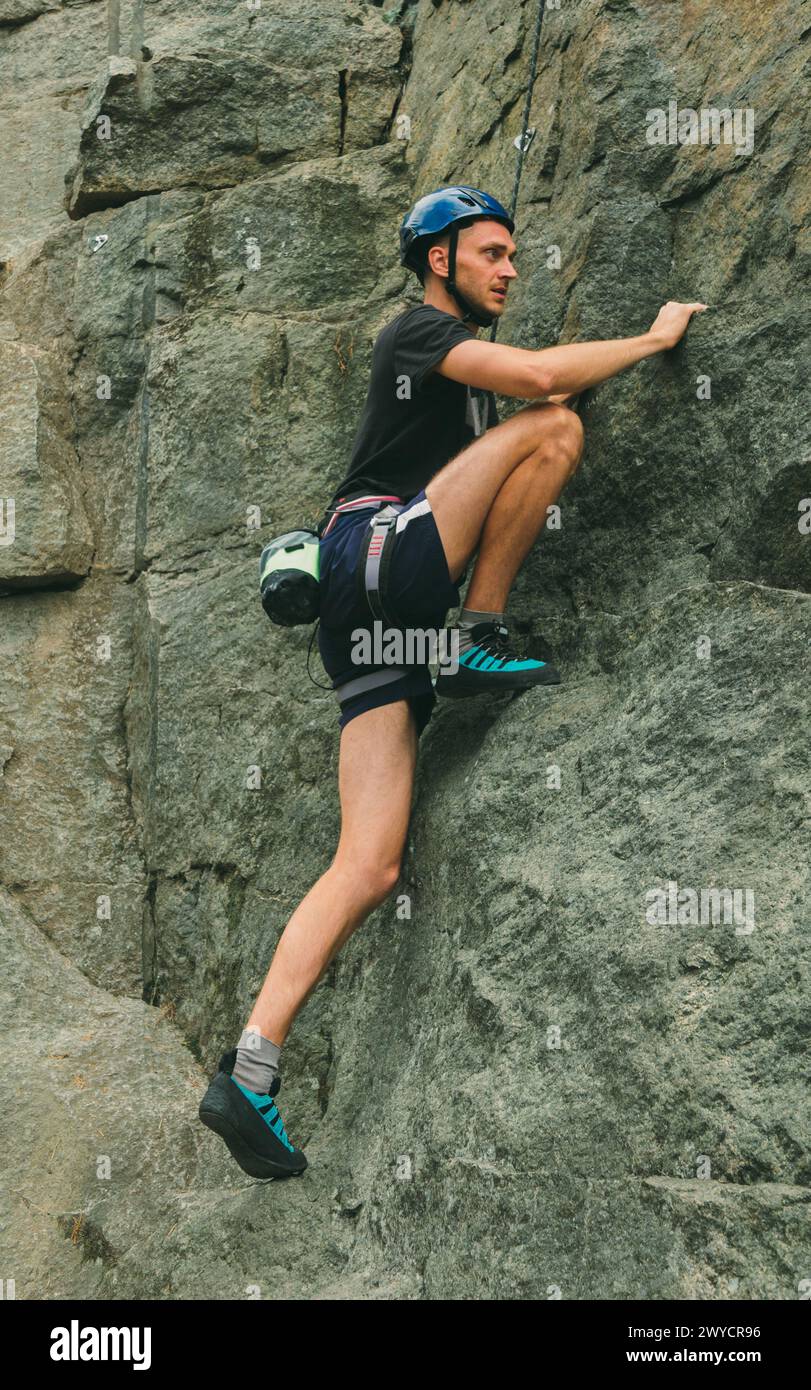 Giovane con attrezzature che fa arrampicata all'aperto. Area di allenamento per attività all'aperto. Sport estremi. Foto Stock