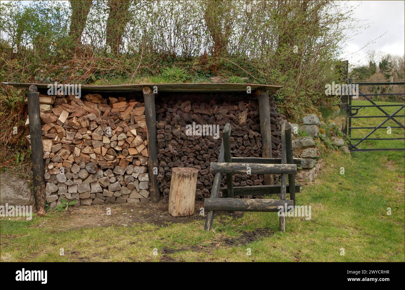 Pile di legno e torba pronti per l'inverno sotto un riparo di legno Foto Stock