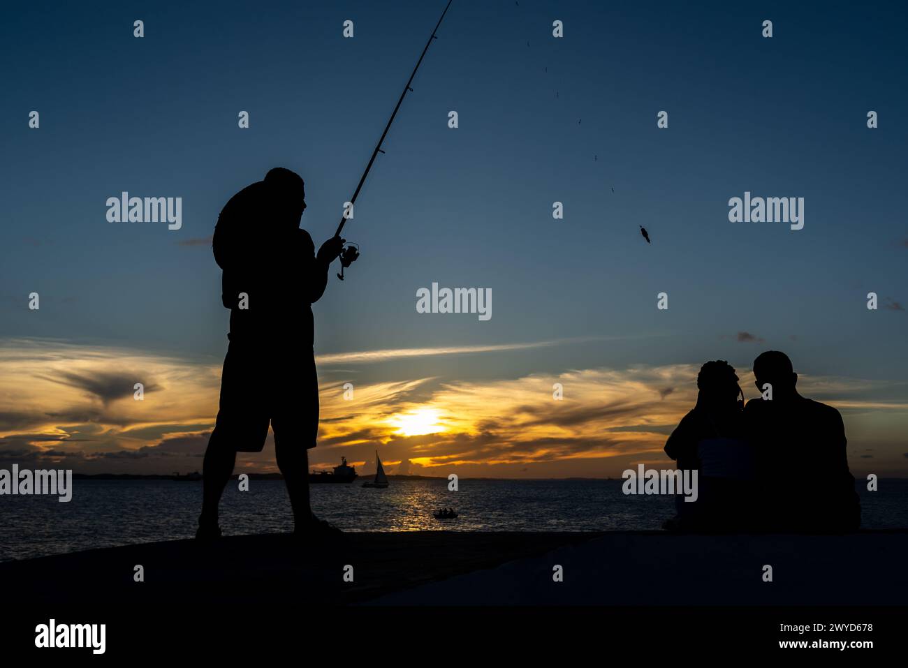 Salvador, Bahia, Brasile - 13 aprile 2019: Il pescatore viene visto in silhouette al tramonto a Ponta do Humaita nella città di Salvador, Bahia. Foto Stock