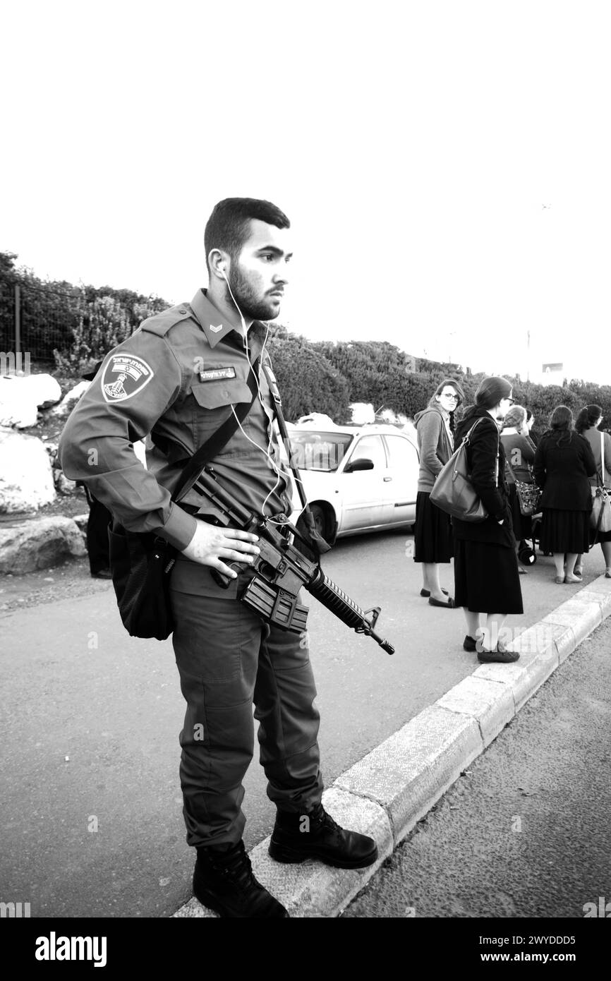 12-25-2014 Gerusalemme. Soldato (in vacanza) con mitragliatrice (TAR-21) dell'esercito israeliano in vacanza alla fermata dell'autobus o del tram. (anche le persone accese Foto Stock