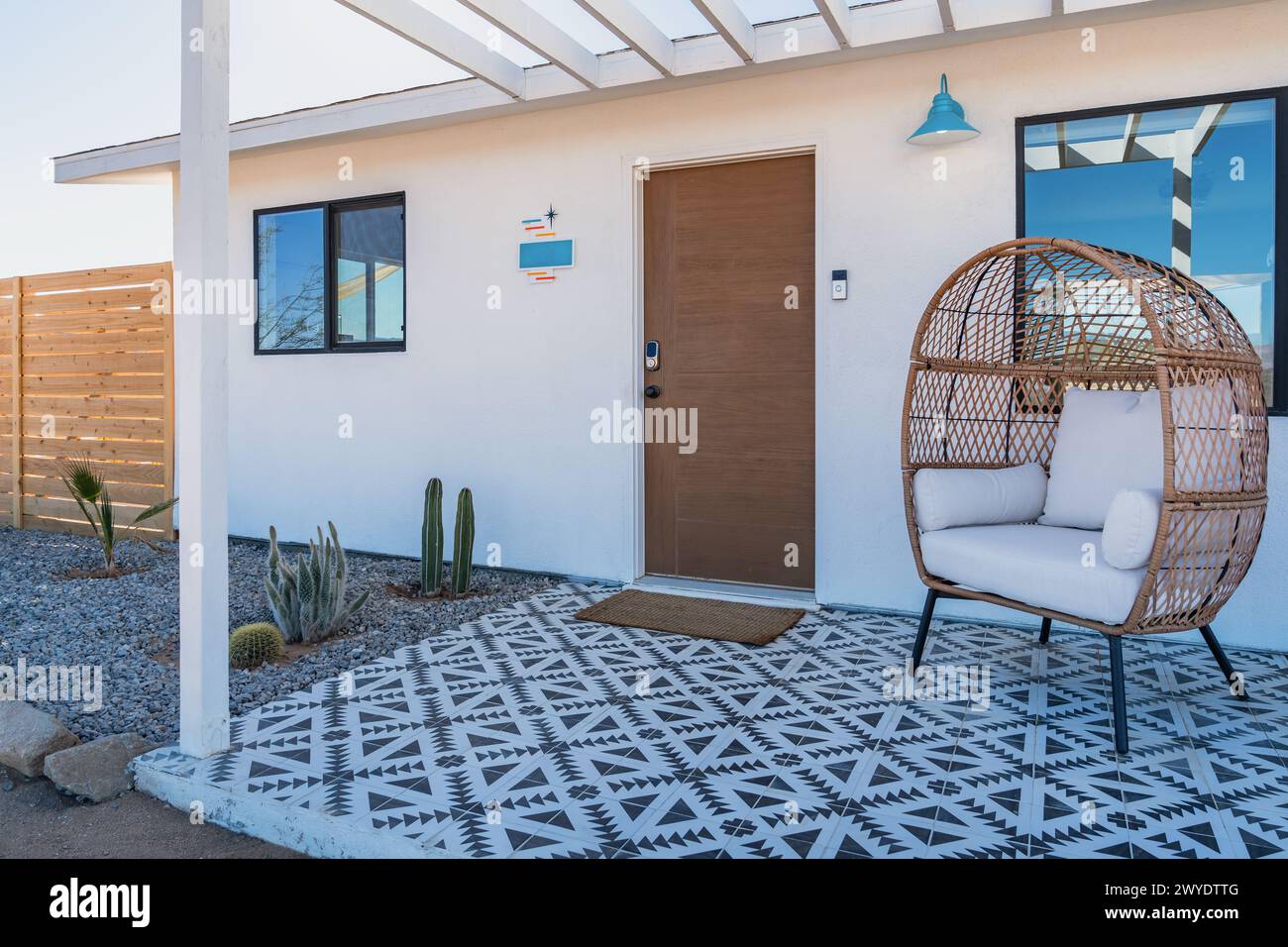 Moderno portico bohémien sul fronte casa deserta con piastrelle e sedia in rattan durante il giorno Foto Stock