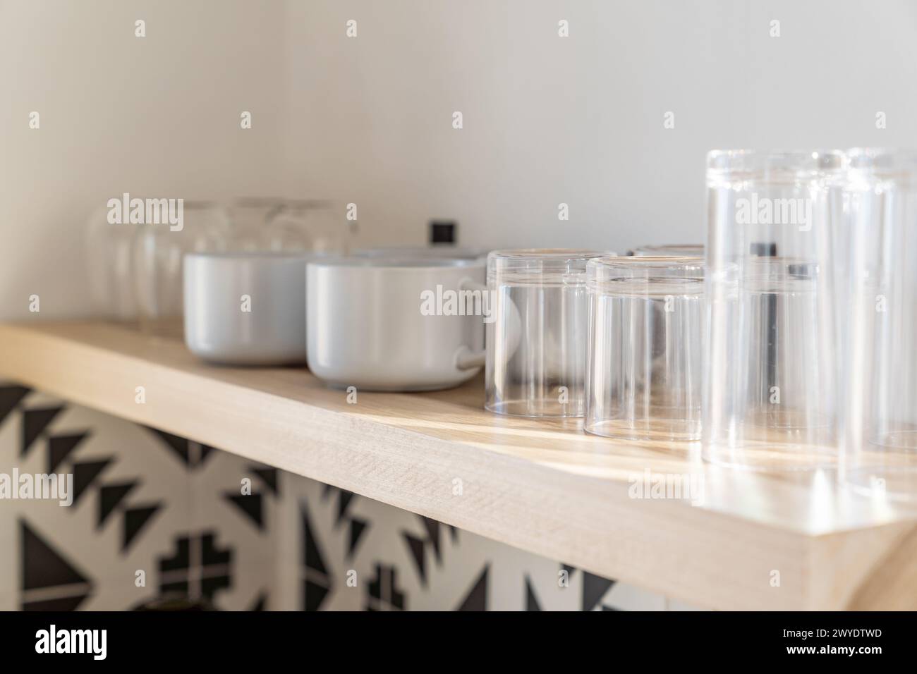 Tazze e bicchieri da caffè su un ripiano galleggiante in legno in una cucina moderna con piastrelle bianche e nere Foto Stock