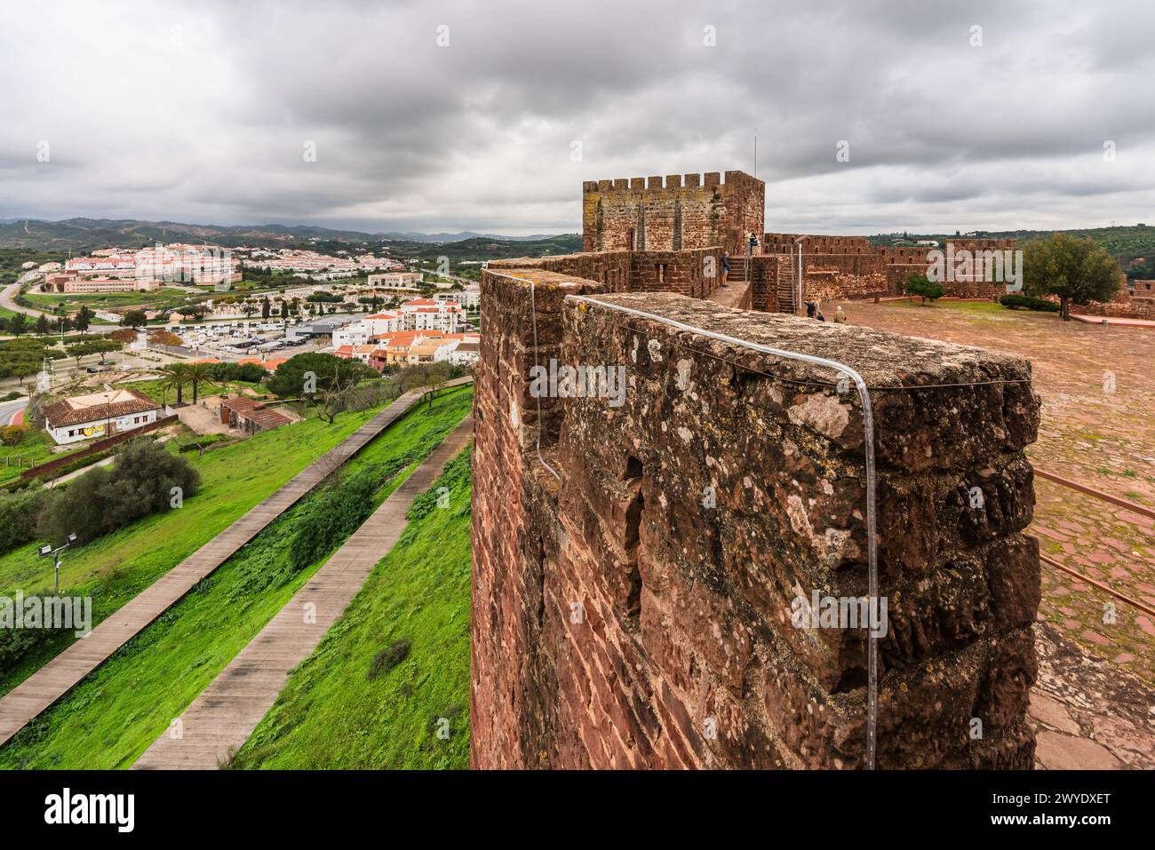 Le robuste mura rosse del Castello di Silves, con un visitatore che si gode la vista dai bastioni. Foto Stock