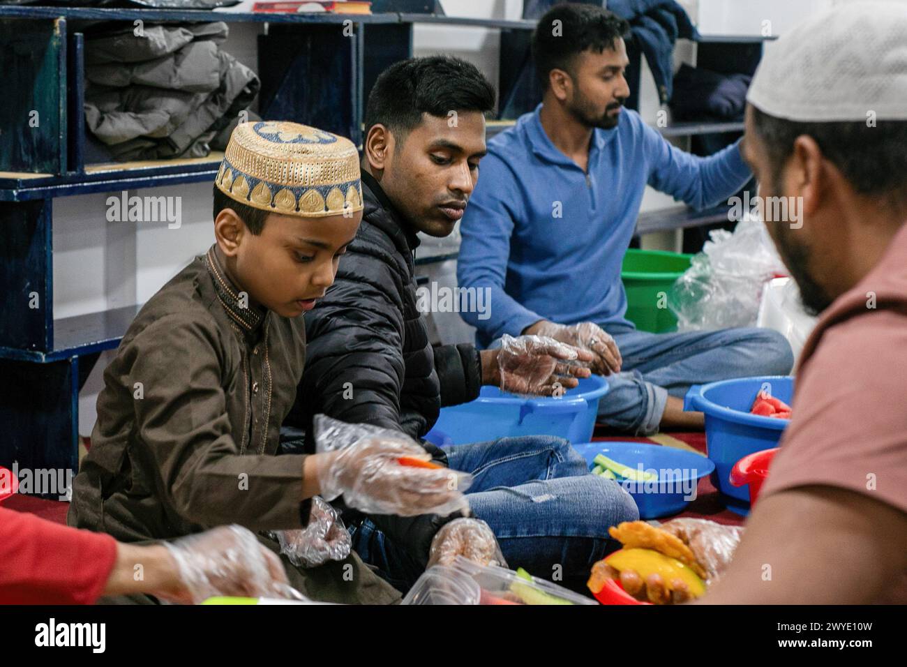 Madrid, Spagna. 5 aprile 2024. Un ragazzo tra un gruppo di uomini collabora nella preparazione del cibo prima dell'iftar (rompendo il digiuno) in una moschea di Madrid. Open Days e cena promossi dalla Valiente Bangla Association durante il Ramadan. Celebrato alla moschea "Baitul Mukarram" nel quartiere Madrid di Lavapiés. Credito: SOPA Images Limited/Alamy Live News Foto Stock