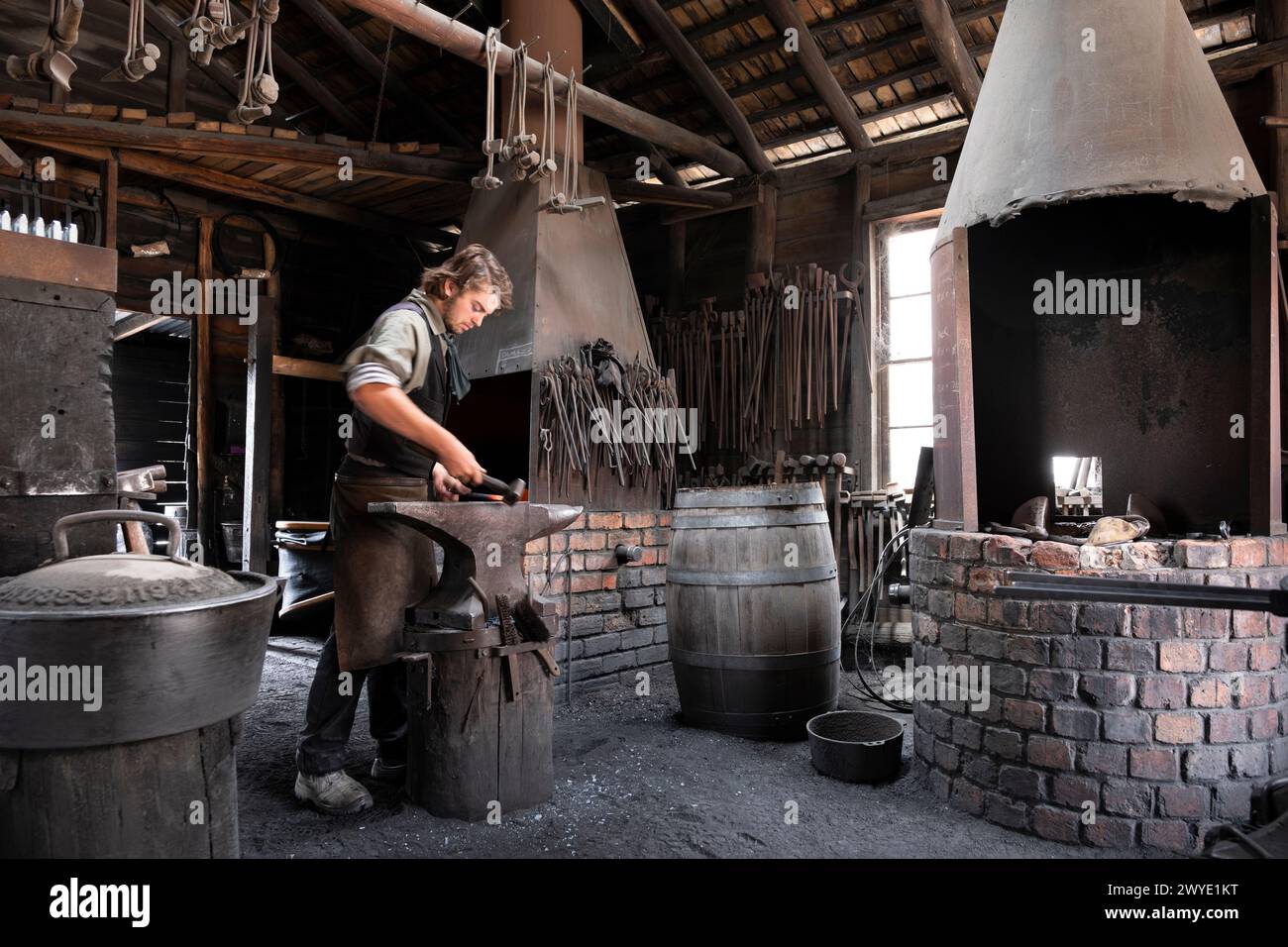 Il fabbro colpisce la ferriera (sfocatura del movimento) sull'incudine con il martello in una vecchia fucina storica al G.. M Dilges' fabbro Foto Stock