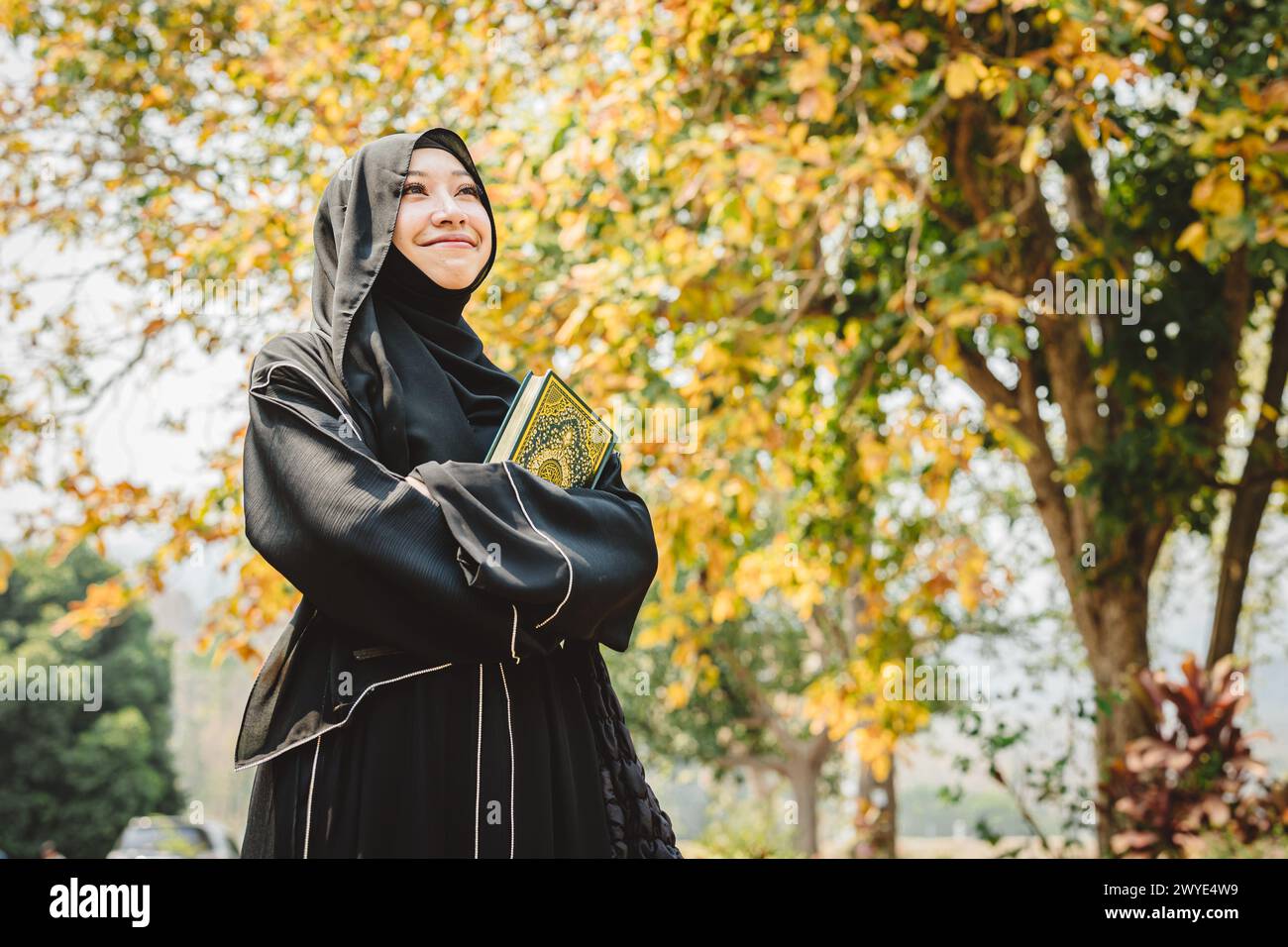 La donna musulmana del niqab legge e impara il Corano e la fede il libro del Santo al Corano. Donna araba del chador nero saudita. Foto Stock