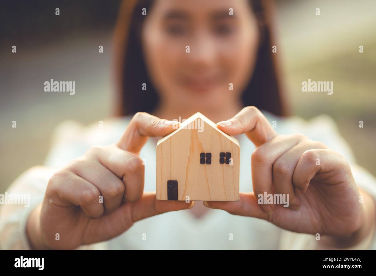 persone che tengono a mano il modello di casa in legno in miniatura per l'edilizia bancaria mutuo affitto immobiliare affitto casa concetto di famiglia Foto Stock