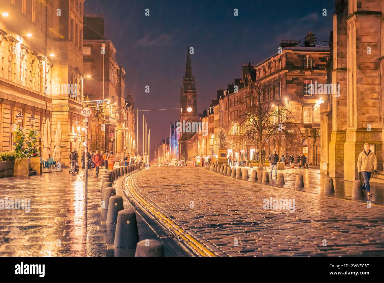 Edimburgo, Scozia - 22 gennaio 2024: Strade e marciapiedi acciottolati bagnati riflettono il semaforo lungo il Royal Mile nella città vecchia di Edimburgo Foto Stock