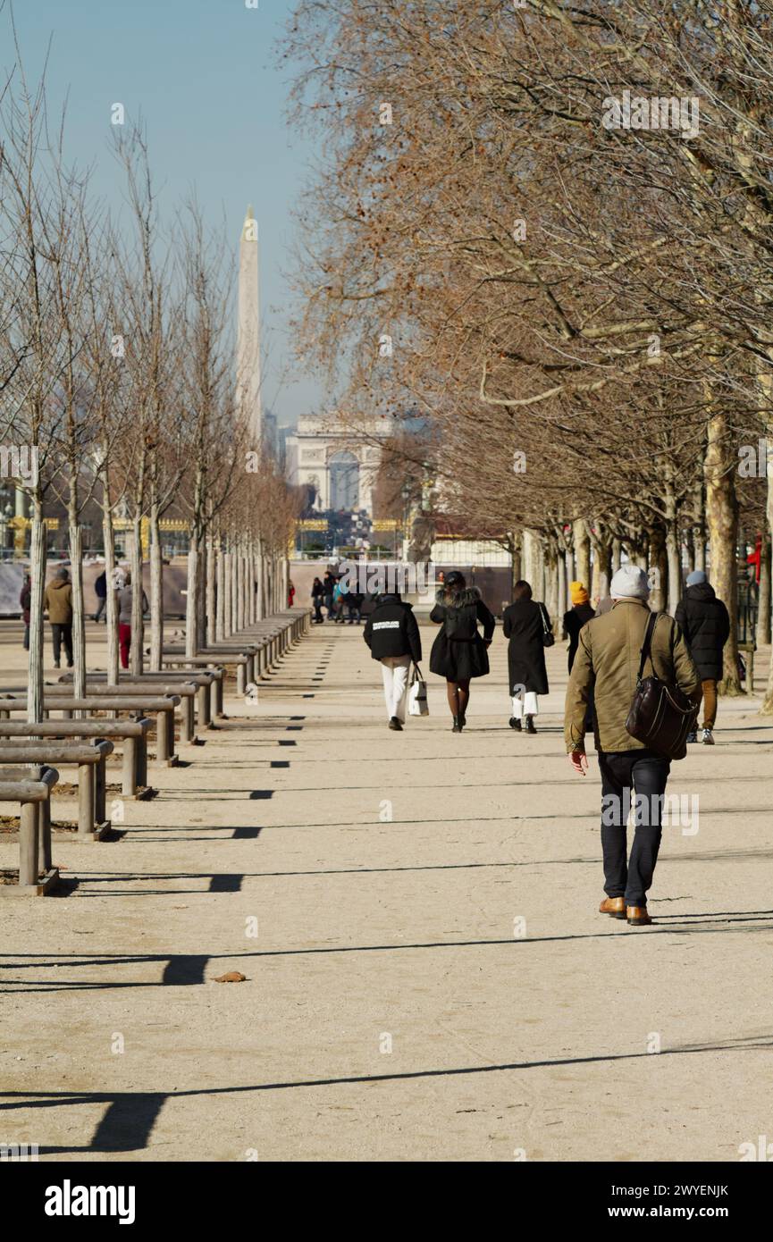 Abbigliamento uomo d'inverno passeggiando per i Jardin Des Tuileries con l'Arco di Trionfo e Place De la Concorde sullo sfondo, Parigi Francia Foto Stock