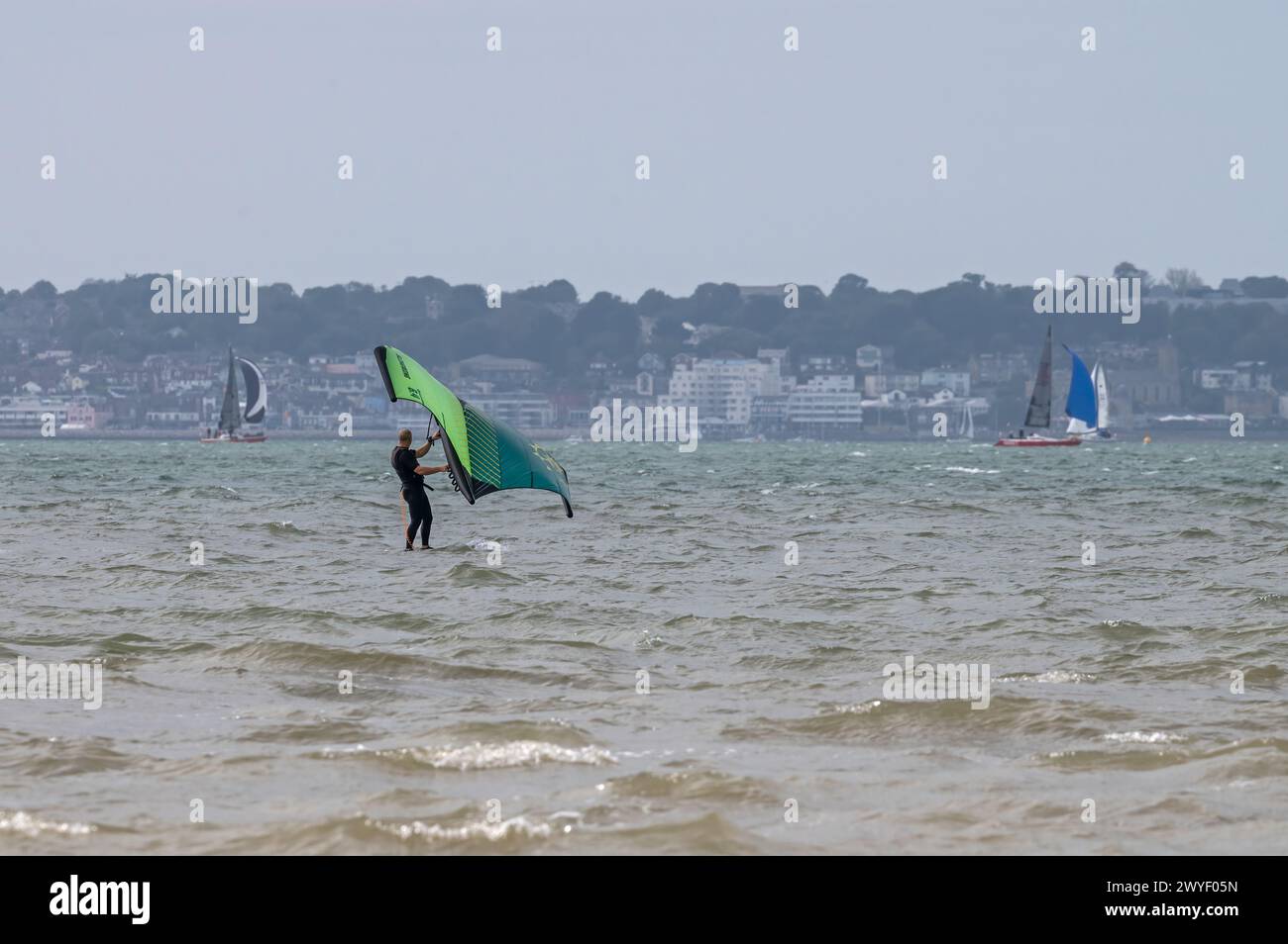 Kite surfisti e windsurfisti che sfruttano al massimo una giornata di blustery sul Solent a Stokes Bay, Lee-on-Solent, Gosport Hampshire, Inghilterra, Regno Unito Foto Stock