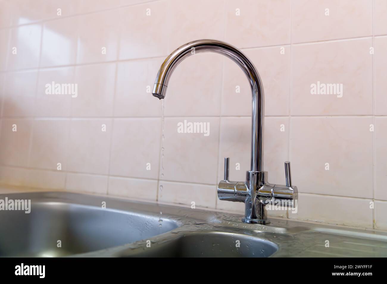 Un rubinetto gocciolante spreca l'acqua ma sembra rinfrescante Foto Stock