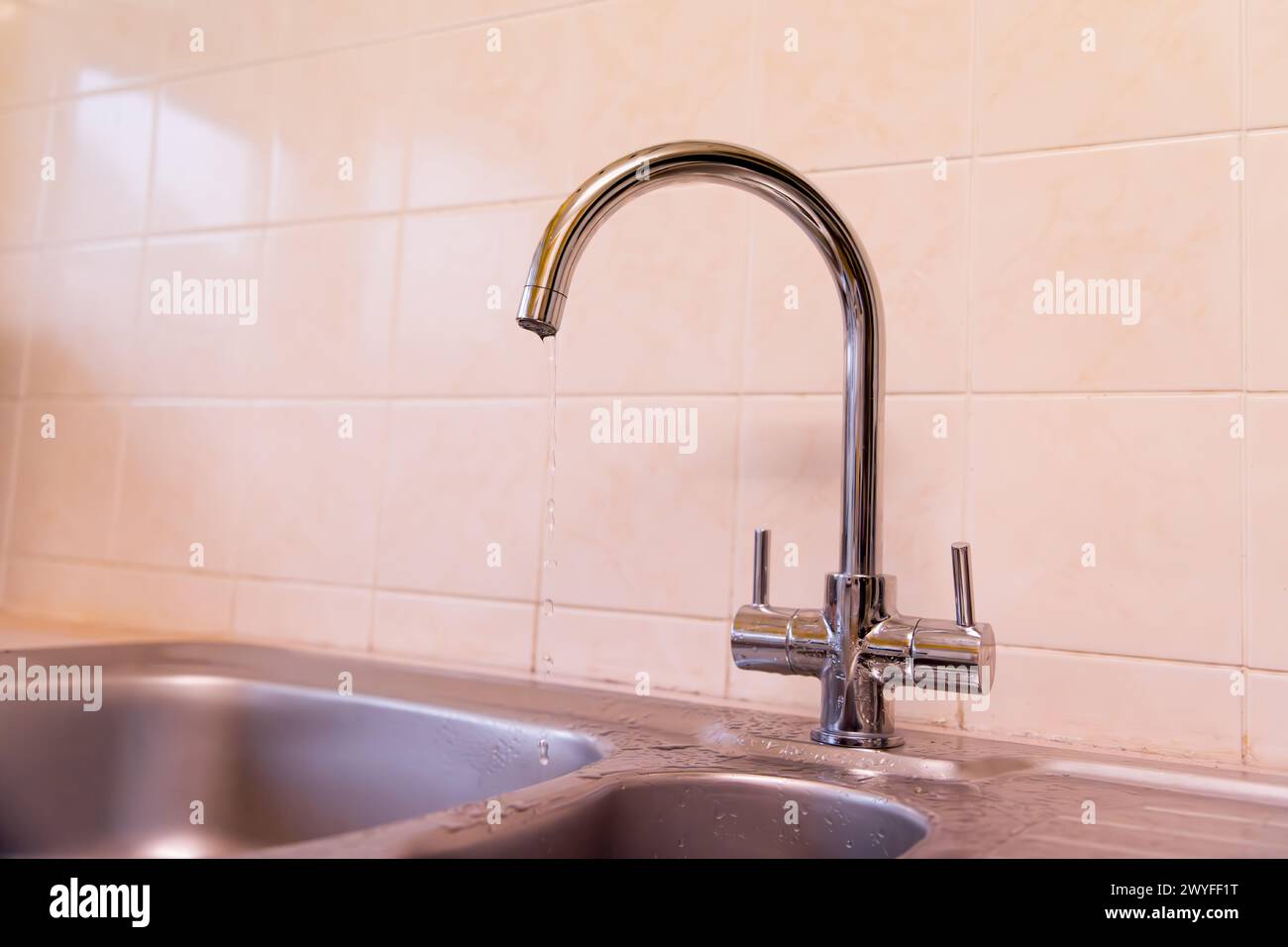 Un rubinetto gocciolante spreca l'acqua ma sembra rinfrescante Foto Stock
