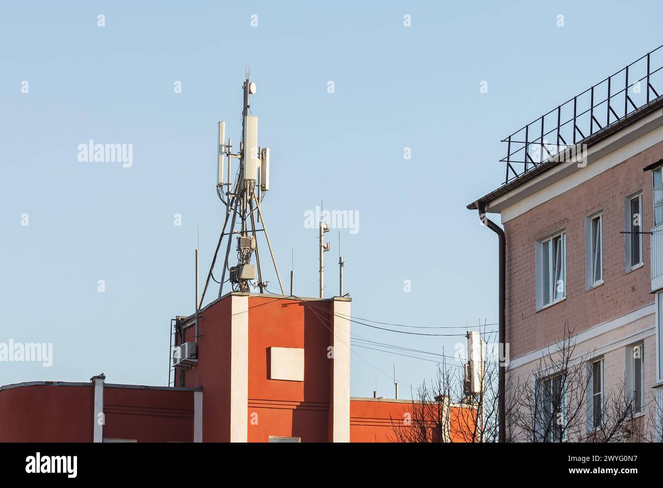 Torri cellulari sul tetto di un edificio vicino a edifici residenziali, un concetto sul tema degli effetti pericolosi delle onde radio sulla salute umana Foto Stock