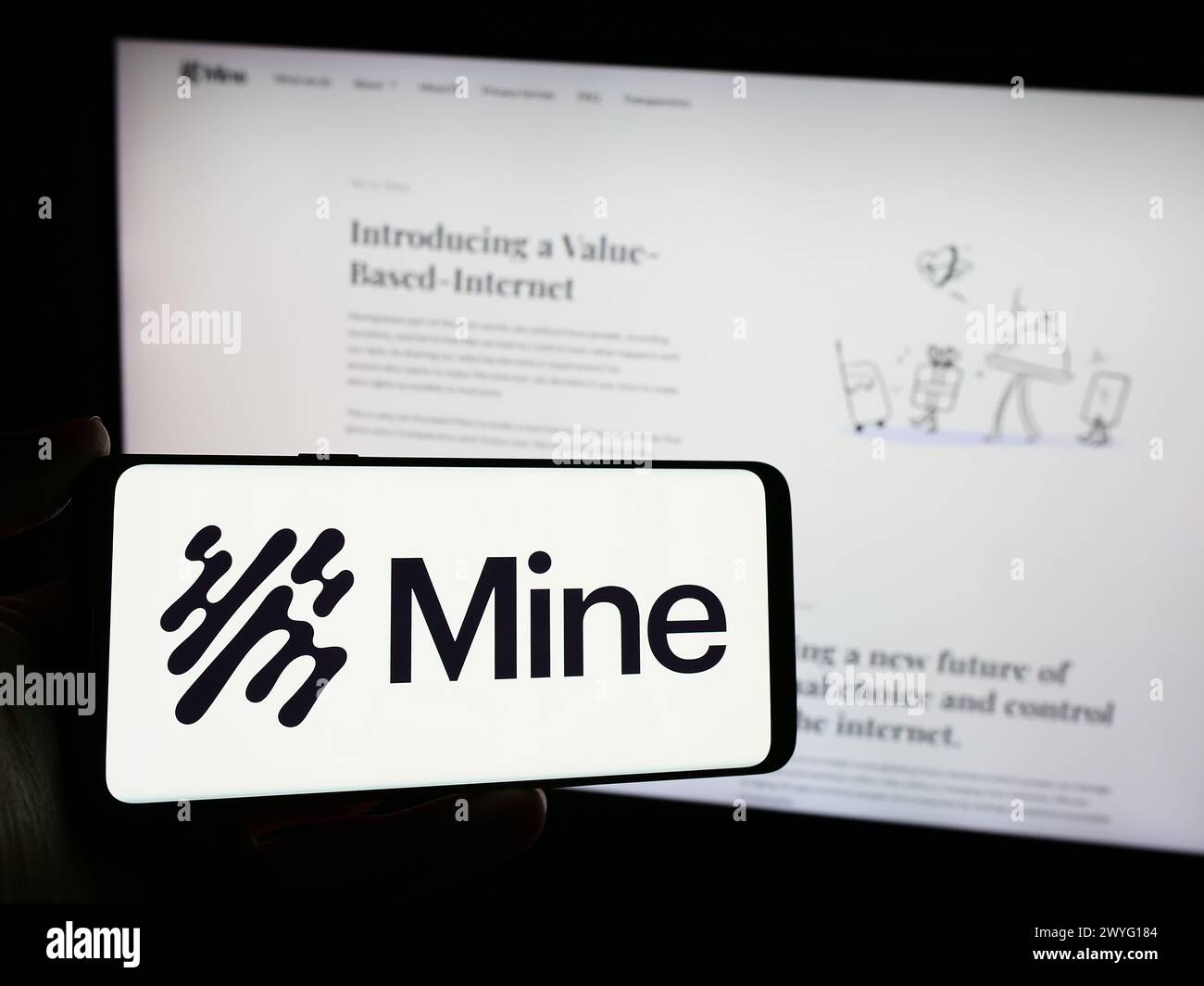 Persona che detiene un telefono cellulare con il logo della società del sistema operativo Saymine Technologies Ltd. (Mio) di fronte alla pagina web. Mettere a fuoco il display del telefono. Foto Stock