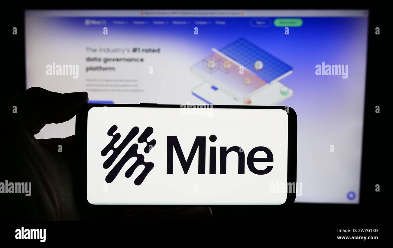 Persona che detiene un cellulare con il logo della società del sistema operativo Saymine Technologies Ltd. (Mio) di fronte alla pagina web. Mettere a fuoco il display del telefono. Foto Stock