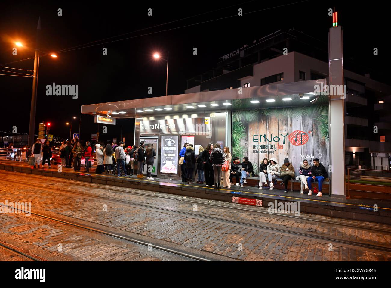 Fermata del tram di notte con persone in attesa dell'arrivo del tram, treni di fronte, Granada, Andalusia, Spagna Foto Stock