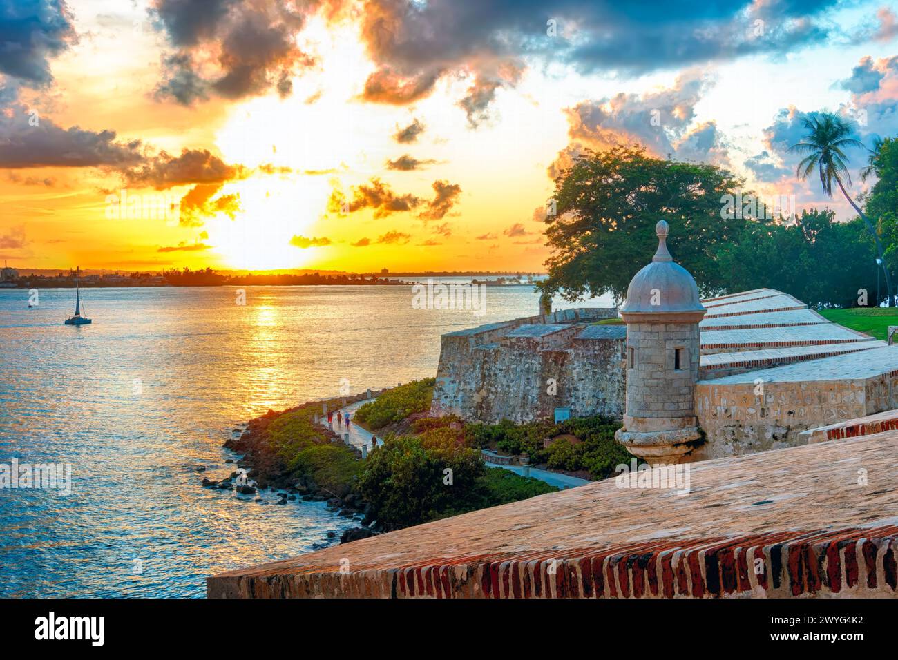 Vista ad angolo alto della Baia di San Juan con le mura della città di San Juan e il Paseo del Morro al tramonto, Porto Rico Foto Stock