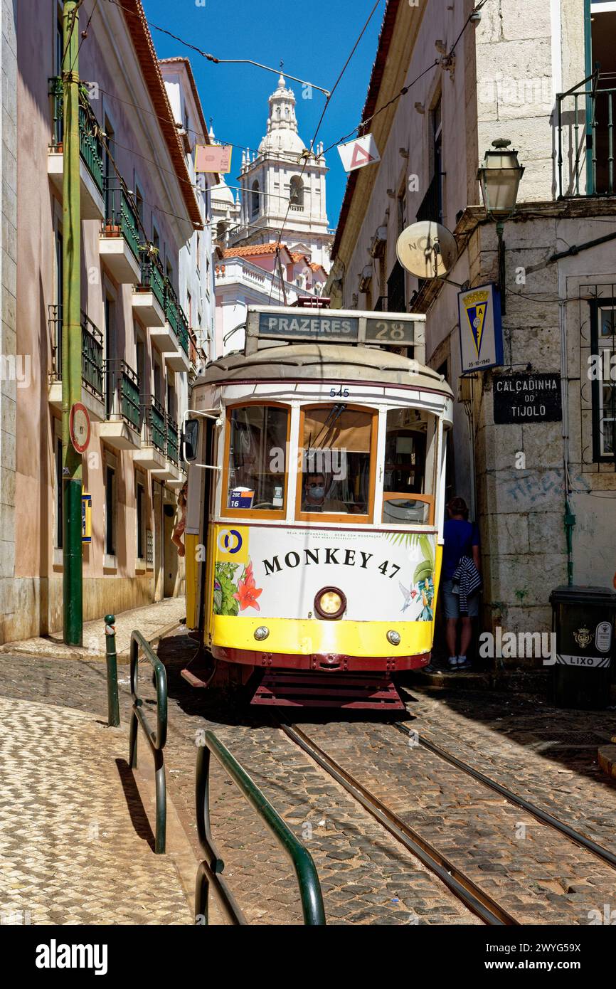 Un tram classico che scende da una collina nel quartiere di Alfama, Lisbona, Portogallo Foto Stock