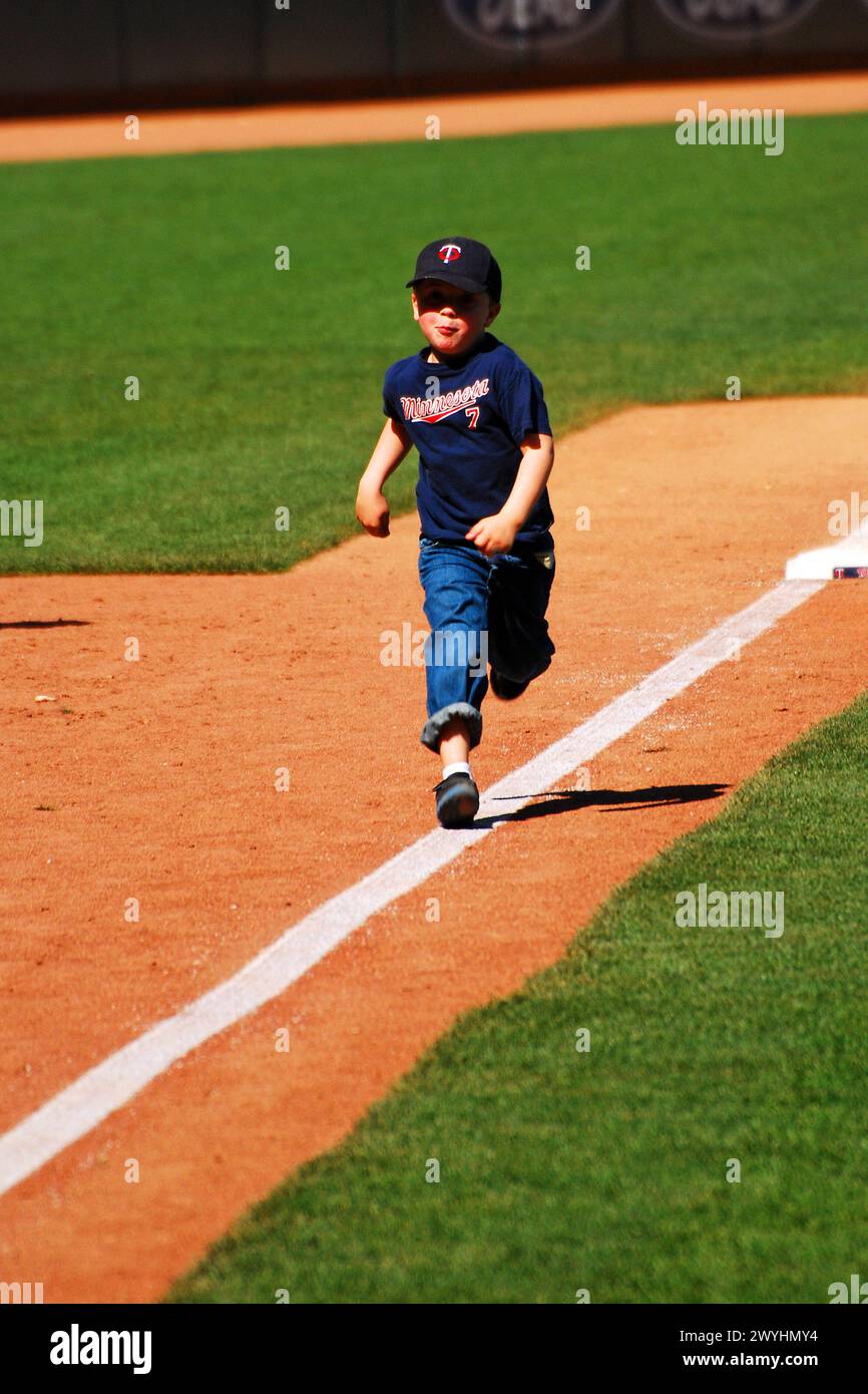 Un giovane ragazzo gira per la terza base e si dirige a casa in una corsa post-partita delle basi allo stadio di baseball Target Field, sede dei Minnesota Twins Foto Stock