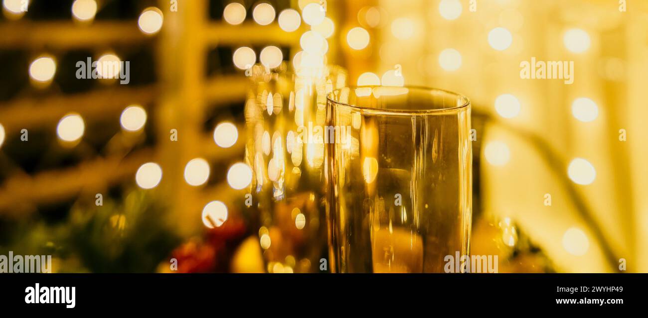 Due bicchieri di champagne ripieni di champagne sono collocati su un tavolo con disposizione a base di frutta. Gli occhiali sono circondati da luci che creano un'atmosfera festosa Foto Stock
