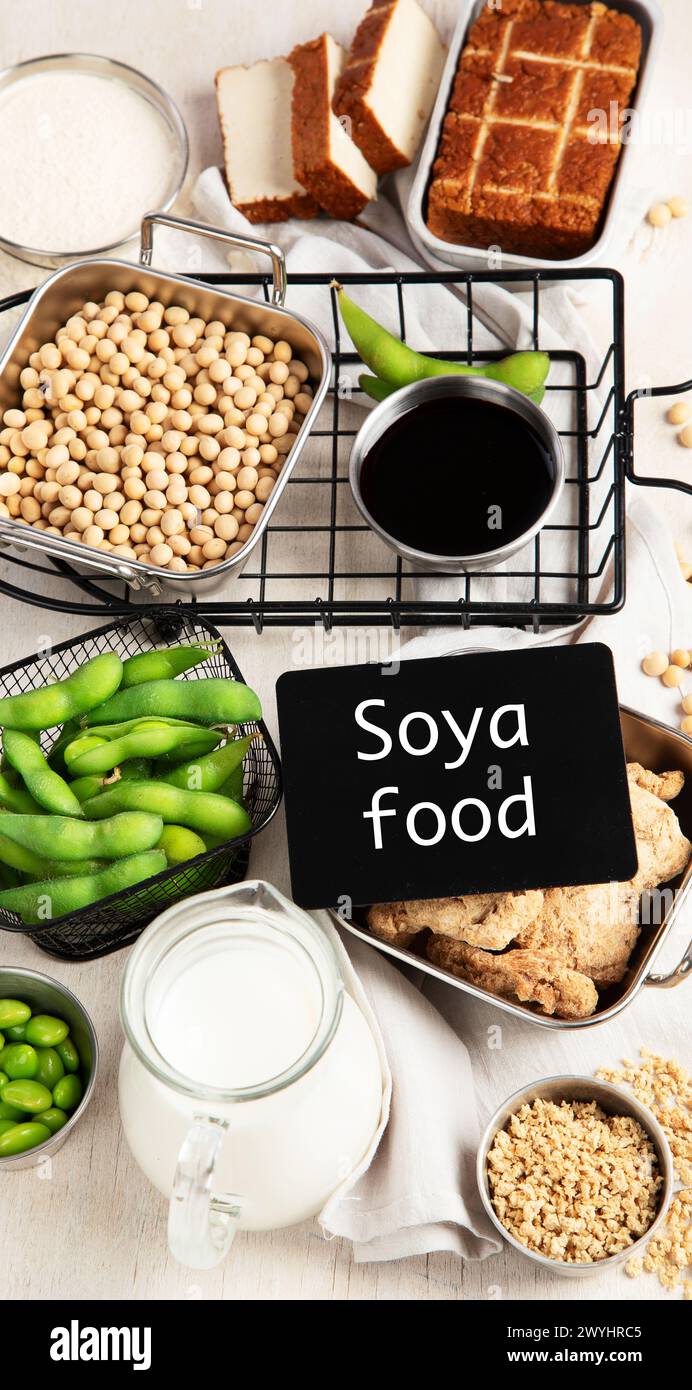 Vari prodotti di soia con semi di soia, tofu, salsa di soia e latte di soia su sfondo chiaro. Vista dall'alto Foto Stock