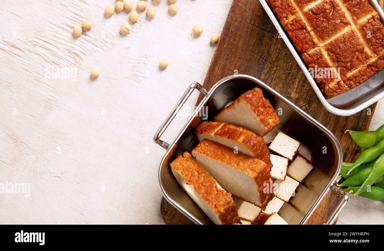 Cibo di soia. Tofu al forno su tavola, semi di soia. Prodotto vegano. Vista dall'alto, copia spazio Foto Stock