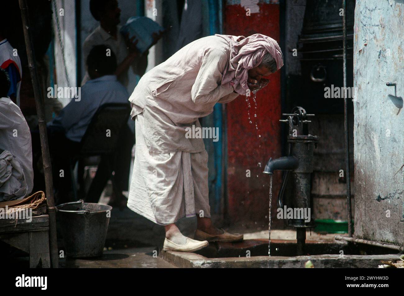 Uomo che beve da PUMP in strada, preso nel 1992, quartiere di Old Delhi, nuova Delhi, India Foto Stock