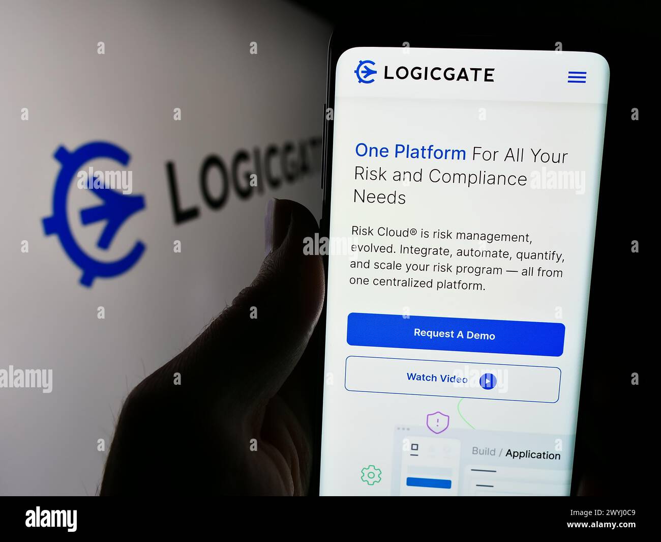 Persona che detiene un cellulare con una pagina web del programma statunitense LogicGate Inc. Di fronte al logo. Messa a fuoco al centro del display del telefono. Foto Stock