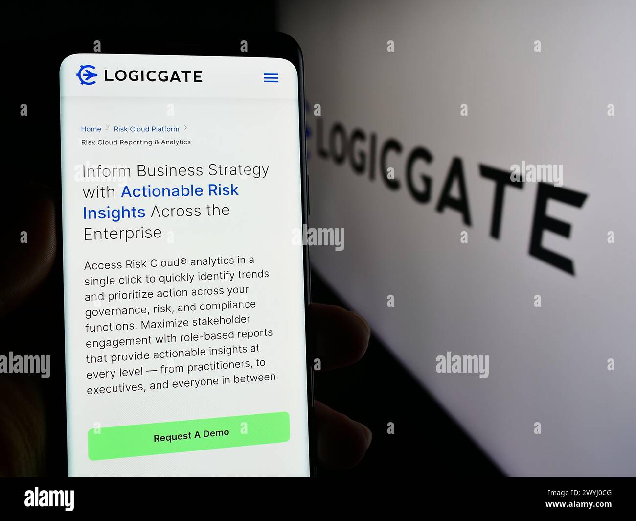 Persona che possiede un telefono cellulare con pagina Web del programma statunitense LogicGate Inc. Con logo. Messa a fuoco al centro del display del telefono. Foto Stock