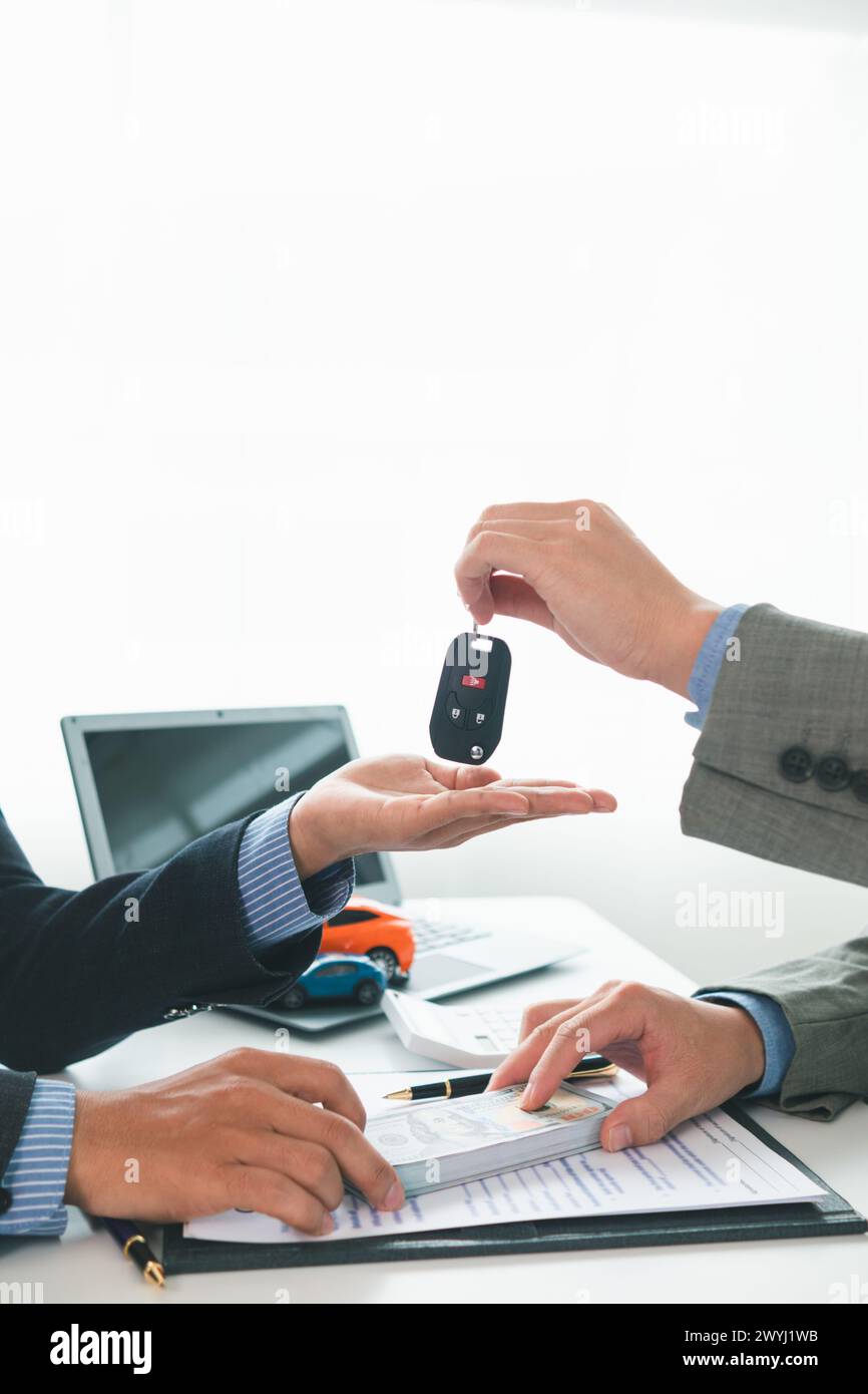 il concessionario sta consegnando le chiavi al cliente dopo la firma del contratto di vendita e del contratto rateale. Concetto di consegna delle chiavi dell'auto a cu Foto Stock