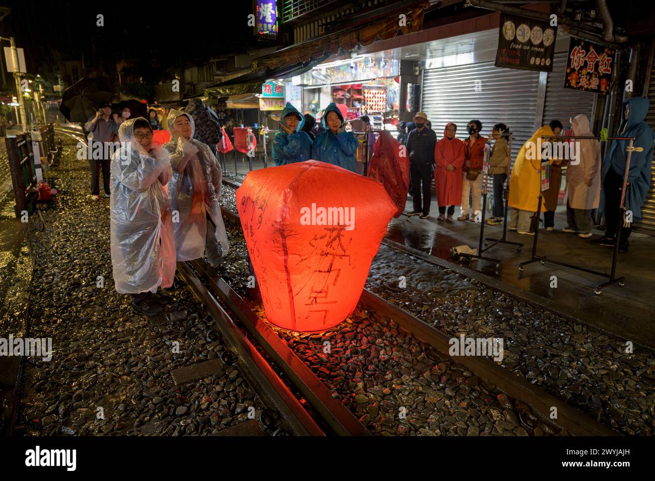 Turisti e curiosi partecipano all'uscita serale di lanterne per augurare il nuovo anno sui binari del treno di Shifen Foto Stock