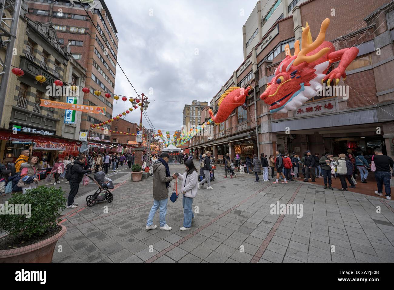 Strada trafficata catturata in pieno giorno con un grande drago cinese sopra la testa, gente che fa shopping per il Capodanno cinese Foto Stock