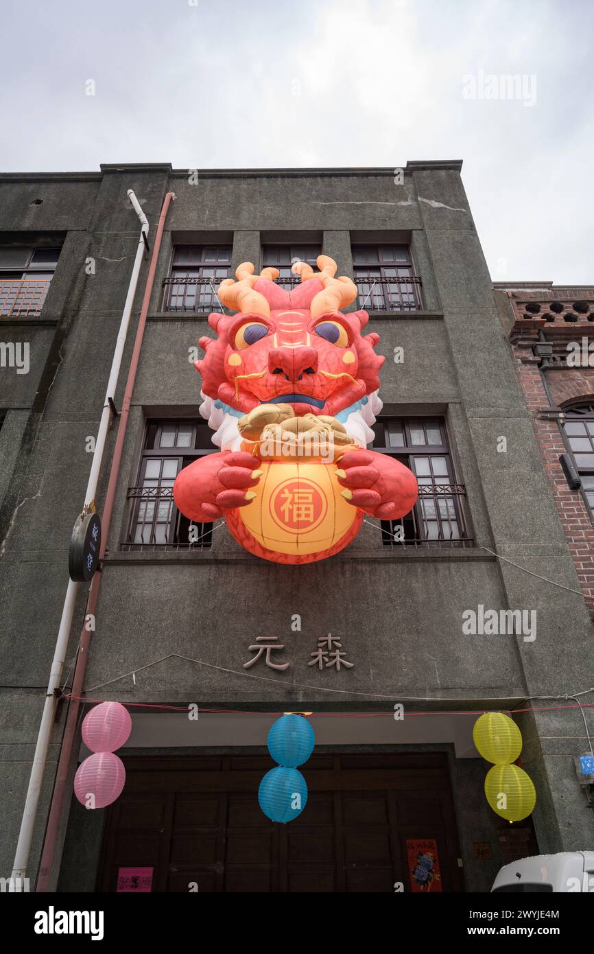 Una grande e colorata scultura di leone con una moneta in bocca adorna l'esterno di un edificio, simboleggiando prosperità e protezione Foto Stock