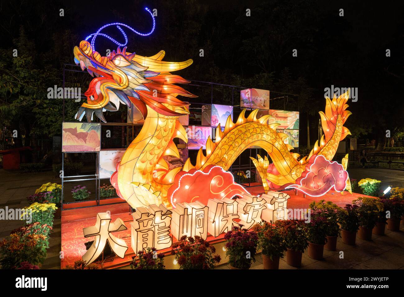 Lanterna a forma di drago luminosa durante un festival notturno, circondata da decorazioni più piccole Foto Stock