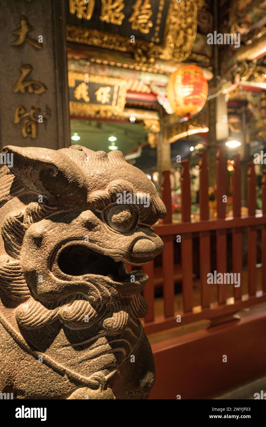Cattura ravvicinata dettagliata di una tradizionale scultura di drago asiatico in un tempio con illuminazione soffusa Foto Stock
